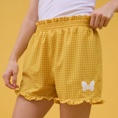 Yellow checkered shorts with a Minnie Mouse bow on a yellow background