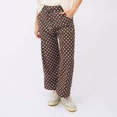 Wrinkle-free women's pants in brown polka dot worn by a woman on a white background