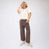 Woman wearing a white top and brown polka dot pants on a white background