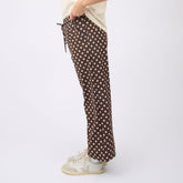 Cute women's pants in brown polka dot print worn by a woman on a white background