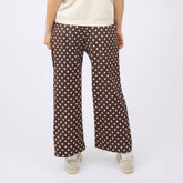 Back view of woman wearing best selling women's pants in brown polka dot print against a white backdrop.