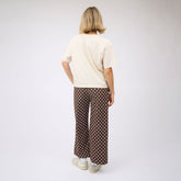 Back view of woman wearing perfect ivory t shirt and women's polka dot pants against a white backdrop.