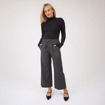 Person wearing a black turtleneck and checkered pants on a white background
