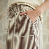 Close up for pocket details on a brown stripe skirt with a blurred background.