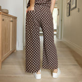 Person wearing a brown polka dot pants in a home setting