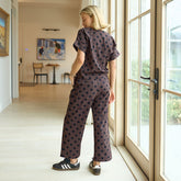 Woman in a polka dot outfit standing by a large window in a home.