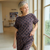 Woman wearing a polka dot outfit standing by a window in a home setting