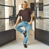 Woman posing in a modern interior setting with large glass doors.