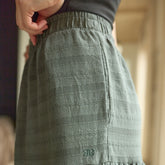 Close up of green textured skirt with a brand logo worn by a woman, blurred background