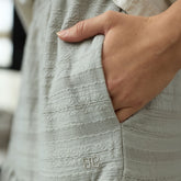Close-up of a hand in a textured taupe garment with a brand logo.