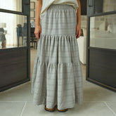 Woman wearing a long neutral taupe maxi skirt in a modern indoor setting