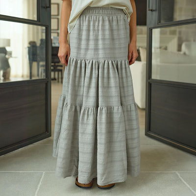 Woman wearing a long neutral taupe maxi skirt in a modern indoor setting
