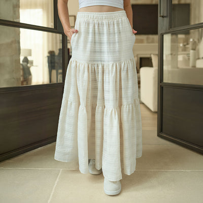Woman wearing a long, off white skirt in an indoor setting.