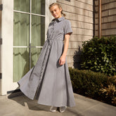 Woman wearing a maxi dress with short-sleeves in navy gingham standing outside a building.