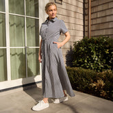 Woman in a navy blue gingham dress standing outside a building with windows.