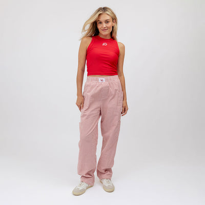 Woman wearing a red tank top and pink pants on a white background