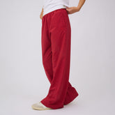 Three-quarter view of red polka dot slip-on trousers showcasing the relaxed wide-leg fit on a model against a light gray background