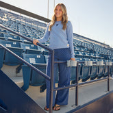 Full-length view of blue and blue polka dot slip-on trousers on a model in stadium seating