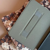 Green fabric case with a pocket on a floral surface