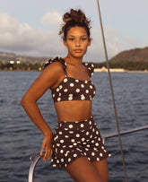 Woman in a polka dot swimsuit on a boat with a scenic background