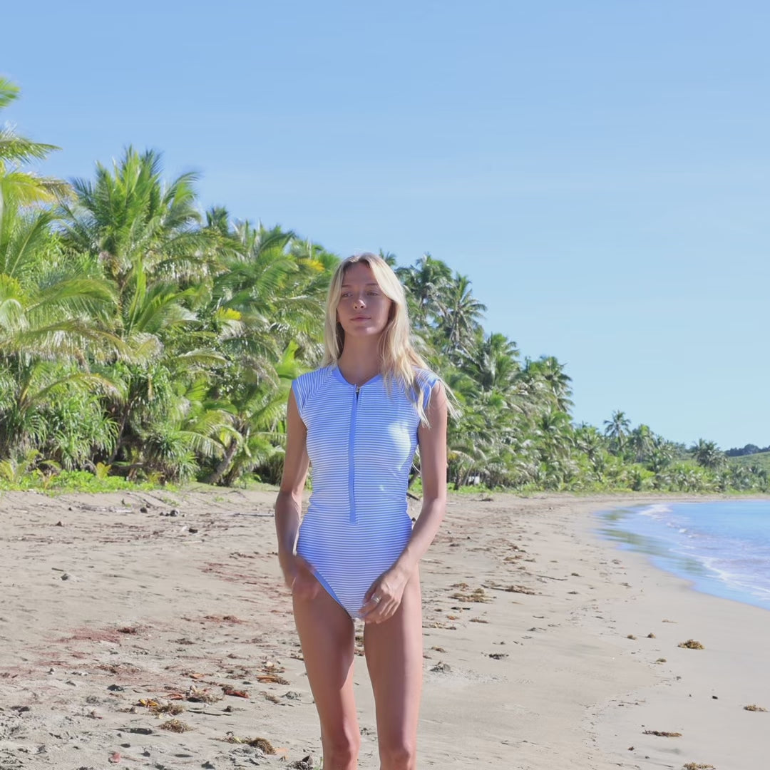 Video of woman on the beach wearing a short sleeved blue swimsuit—the perfect surfing swimsuit for women.