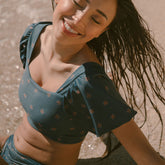 Woman sitting in the ocean in her crop swim top