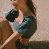 Model wearing Eloise swim crop top sitting in the ocean