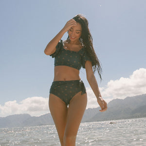 Model standing in the ocean in two-piece bikini