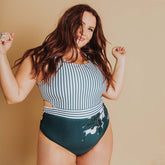 woman dancing in her striped and floral design one-piece swimsuit