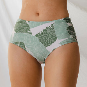 Model wearing high-waisted swim bottoms with palm leaves