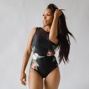 woman modeling a black one-piece swim suit with a floral pattern