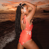 Woman wearing pink one-piece swimsuit at sunset