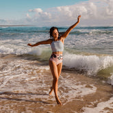 woman at the beach wearing pink high waisted ruched swim bottoms