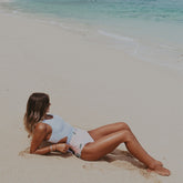 Woman laying on the beach wearing nautical striped one-piece swimsuit