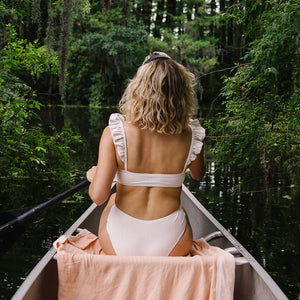 woman in boat wearing white ruffled two piece swimsuit