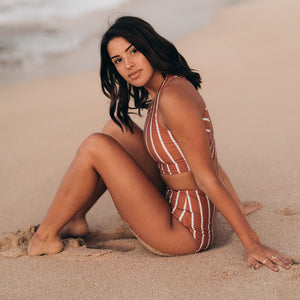 Woman sitting on beach in striped two-piece bikini