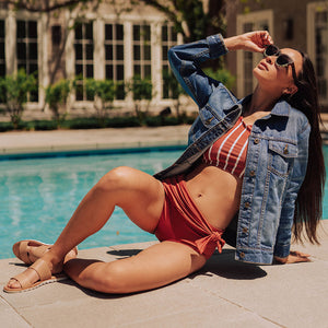 woman laying by pool wearing rust two-piece swimsuit